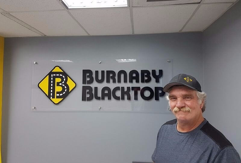 Dave besides Burnaby Blakctop logo